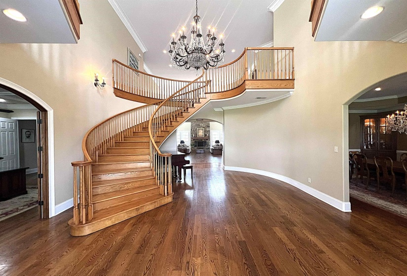 Staircase featuring arched walkways, a chandelier, recessed lighting, crown molding, and wood finished floors