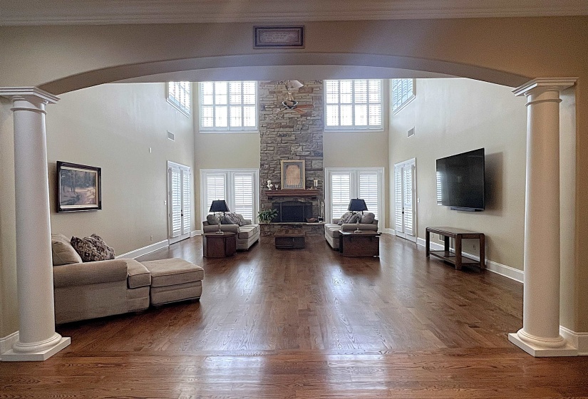 Living area with ornate columns, arched walkways, a towering ceiling, dark wood finished floors, and ornamental molding