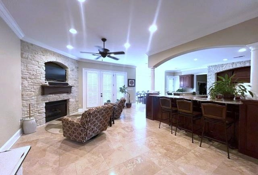 Living room featuring a fireplace, ornate columns, ornamental molding, and a ceiling fan