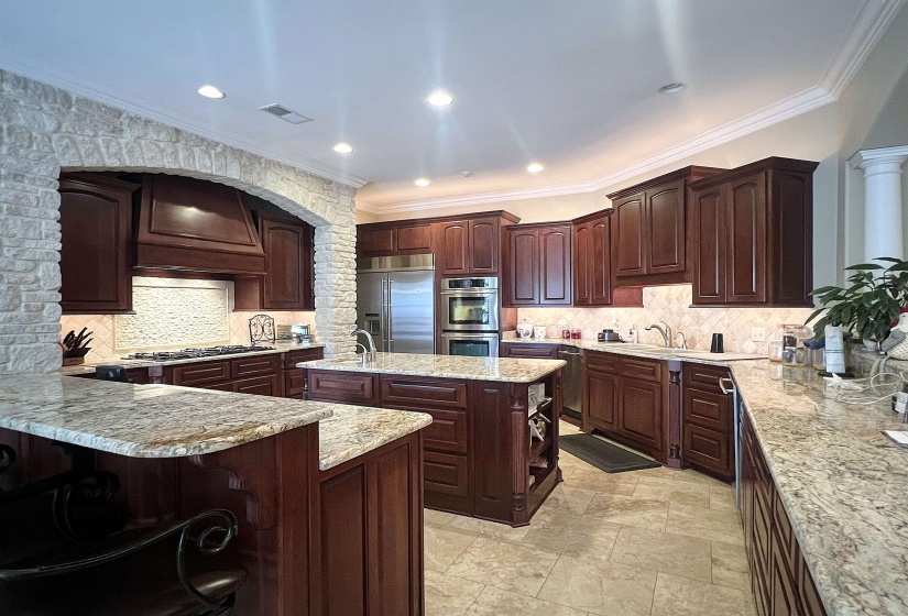 Kitchen with ornamental molding, backsplash, dark brown cabinetry, stainless steel appliances, and a breakfast bar