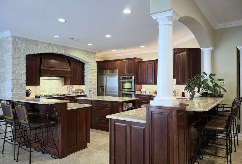 Kitchen featuring a breakfast bar area, a peninsula, crown molding, decorative backsplash, and arched walkways