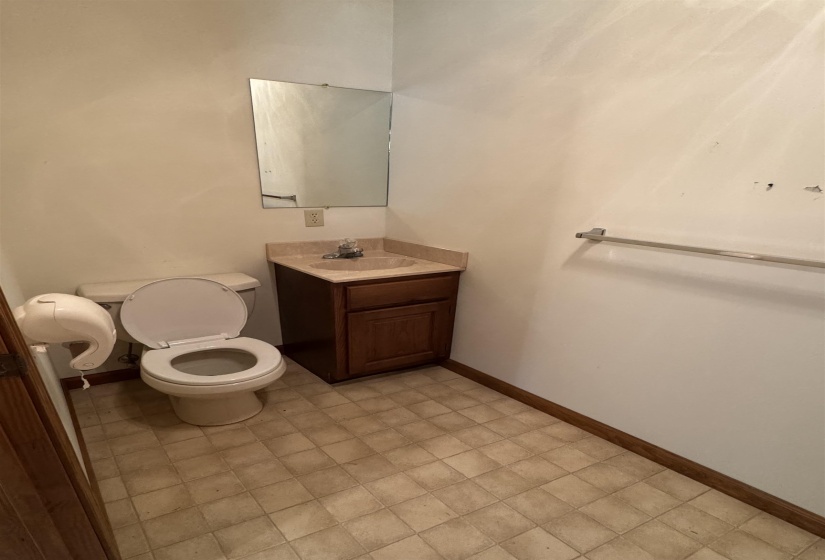 Half bathroom with toilet, baseboards, and vanity