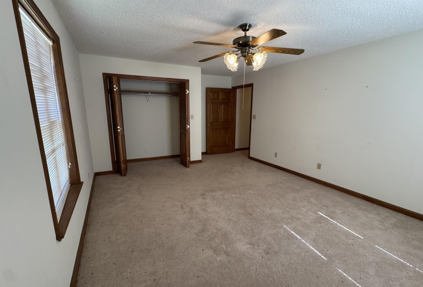 Unfurnished bedroom with a closet, a textured ceiling, light carpet, and a ceiling fan