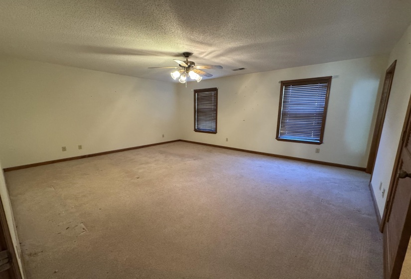Unfurnished room with light colored carpet, a textured ceiling, baseboards, and ceiling fan