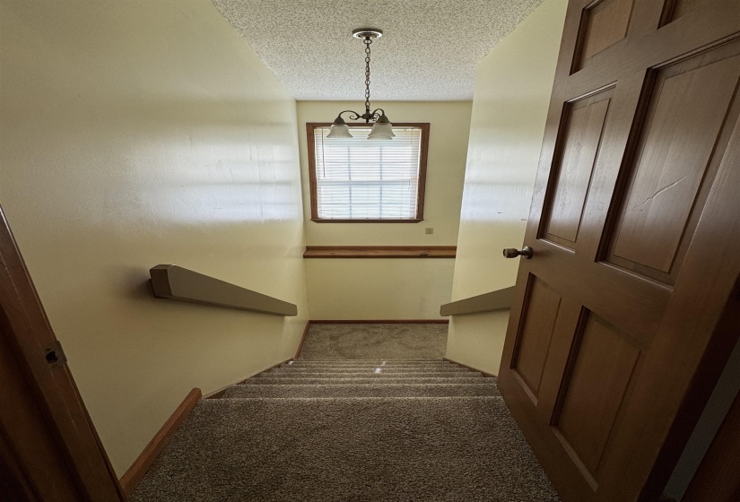 Stairway with a textured ceiling, a chandelier, and carpet