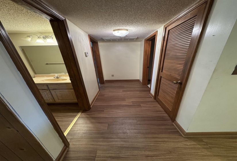 Hall with baseboards, visible vents, a sink, and dark wood-type flooring