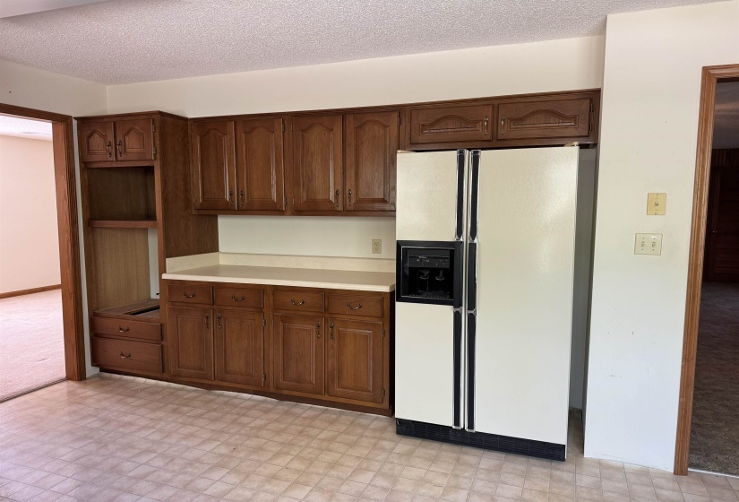 Kitchen featuring white refrigerator with ice dispenser, a textured ceiling, light countertops, and light floors
