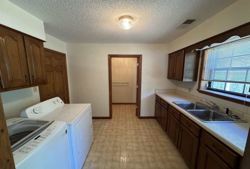 Laundry room featuring a sink, cabinet space, light floors, visible vents, and independent washer and dryer