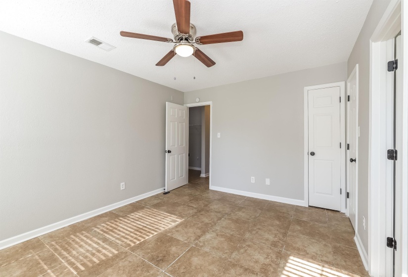 Unfurnished bedroom with light tile flooring and ceiling fan