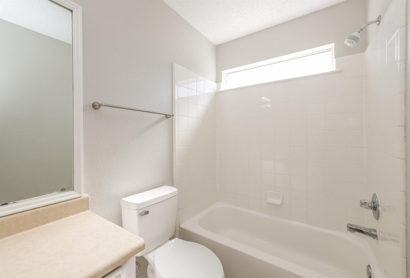 Full bathroom featuring tiled shower / bath, vanity, toilet, and a textured ceiling