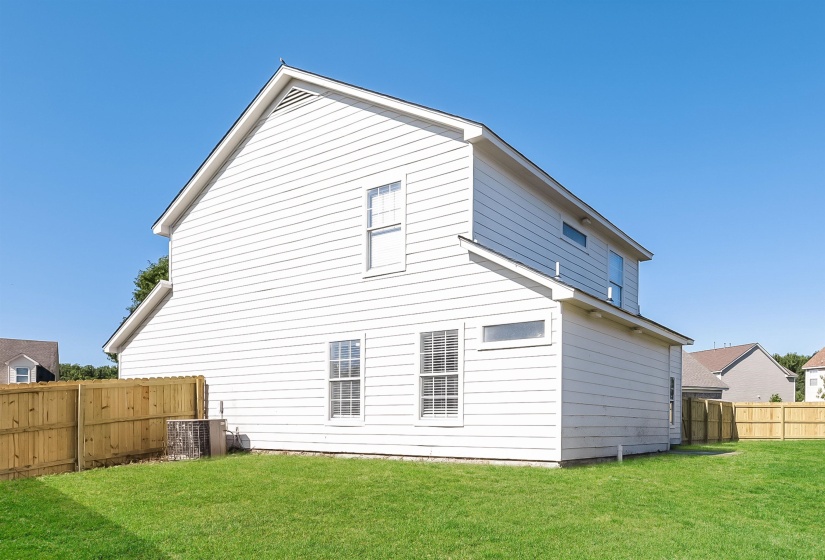 Rear view of house with central AC unit and a yard
