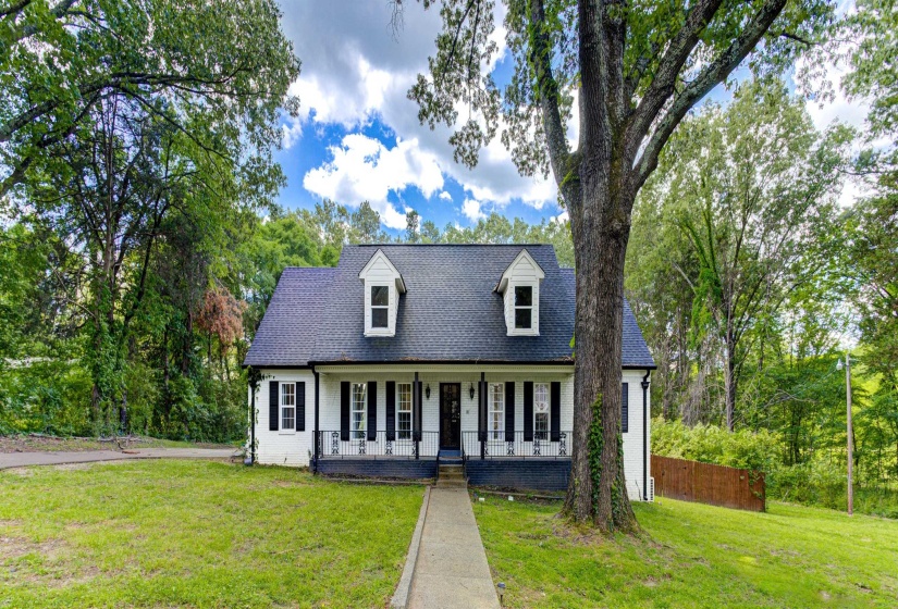Cape cod house featuring covered porch and a front lawn
