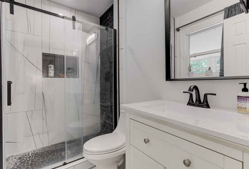 Full bathroom with toilet, vanity, a marble finish shower, and baseboard heating