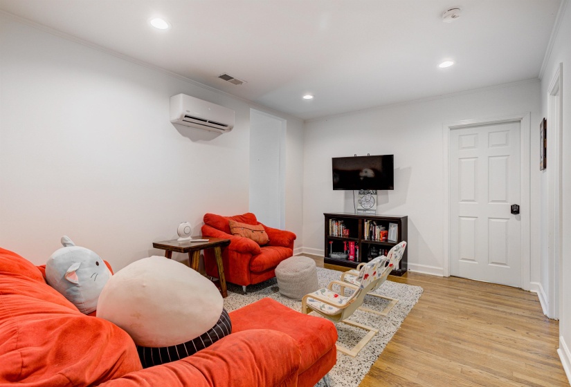 Living area with a wall mounted AC, ornamental molding, recessed lighting, light wood finished floors, and baseboards