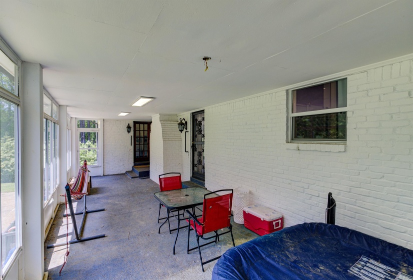 Sunroom with outdoor dining space, plenty of natural light, brick wall, and concrete floors
