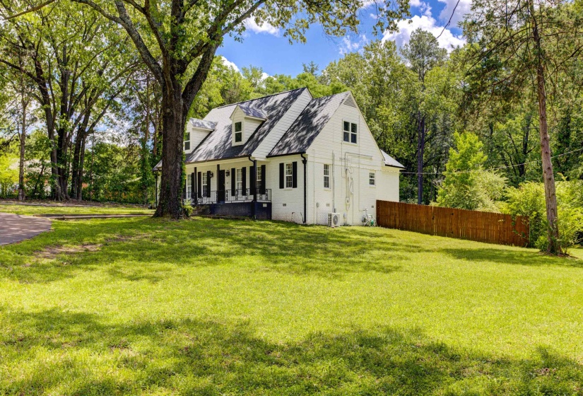 View of property exterior featuring covered porch and view of wooded area