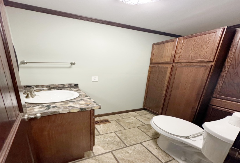Half bath with ornamental molding, vanity, toilet, and baseboards