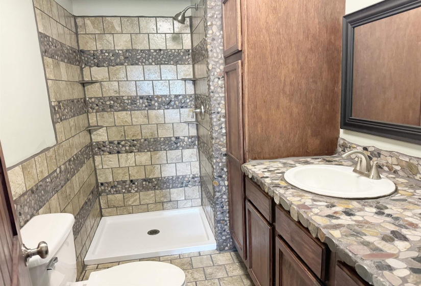 Full bathroom with toilet, a shower stall, vanity, and stone finish floors