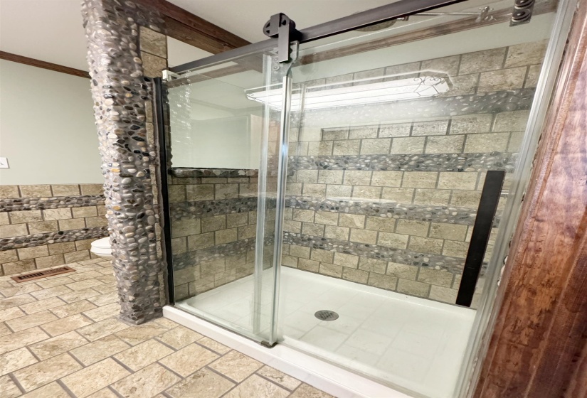 Full bathroom with a stall shower, toilet, ornamental molding, a wainscoted wall, and tile walls