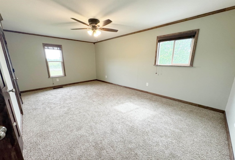 Carpeted spare room featuring ornamental molding, baseboards, and a ceiling fan