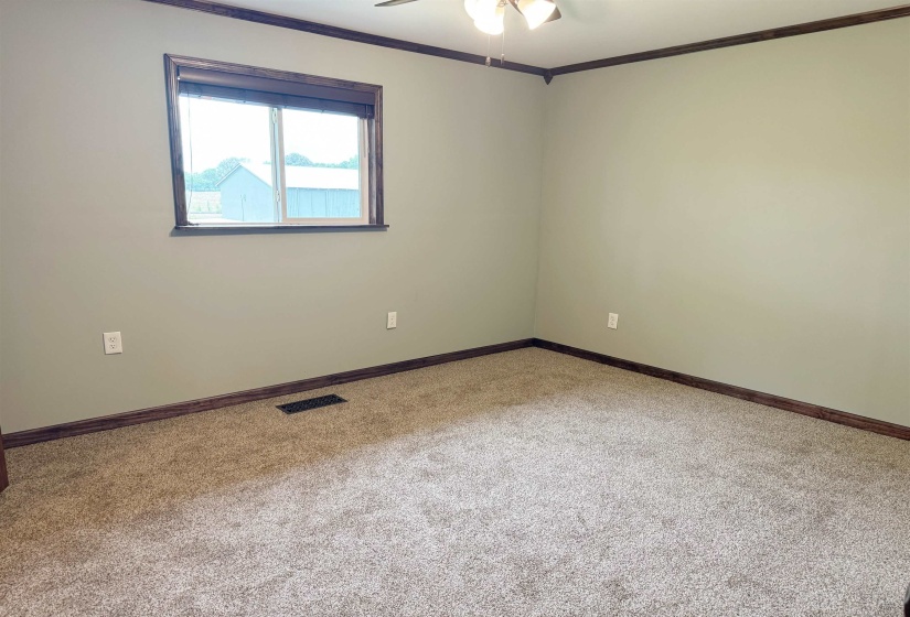 Carpeted spare room with ceiling fan, ornamental molding, and baseboards