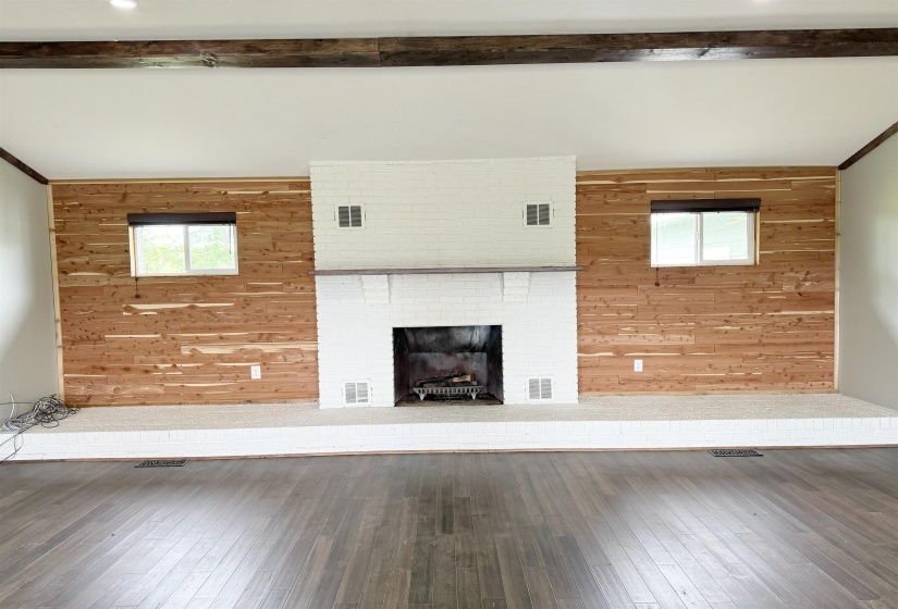 Unfurnished living room with wooden walls, hardwood / wood-style floors, and a fireplace