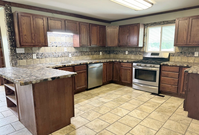 Kitchen featuring stainless steel appliances, a sink, a peninsula, tasteful backsplash, and open shelves