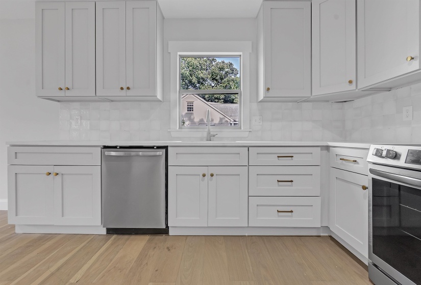 Kitchen featuring appliances with stainless steel finishes, a sink, tasteful backsplash, and light countertops
