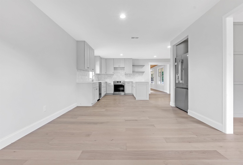 Unfurnished living room featuring baseboards, light wood-style floors, recessed lighting, and a sink