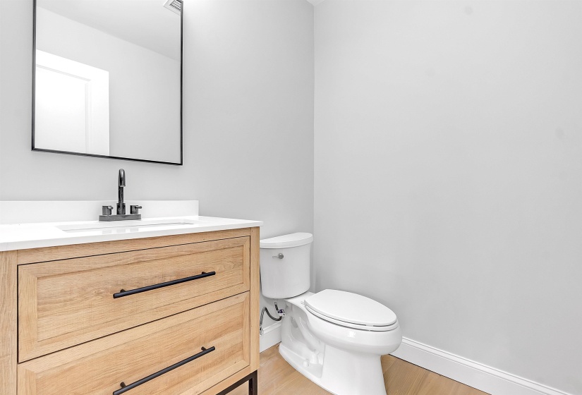 Bathroom with baseboards, toilet, vanity, and wood finished floors