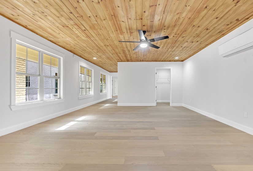 Empty room featuring wooden ceiling, a ceiling fan, baseboards, light wood-style flooring, and a wall mounted AC