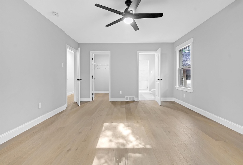 Unfurnished bedroom featuring baseboards, a walk in closet, light wood-style floors, ensuite bathroom, and a closet