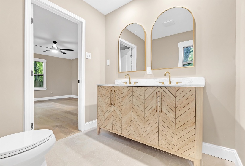 Bathroom with a ceiling fan, baseboards, toilet, and double vanity