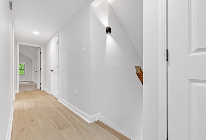 Hall with baseboards, light wood-style floors, vaulted ceiling, and recessed lighting