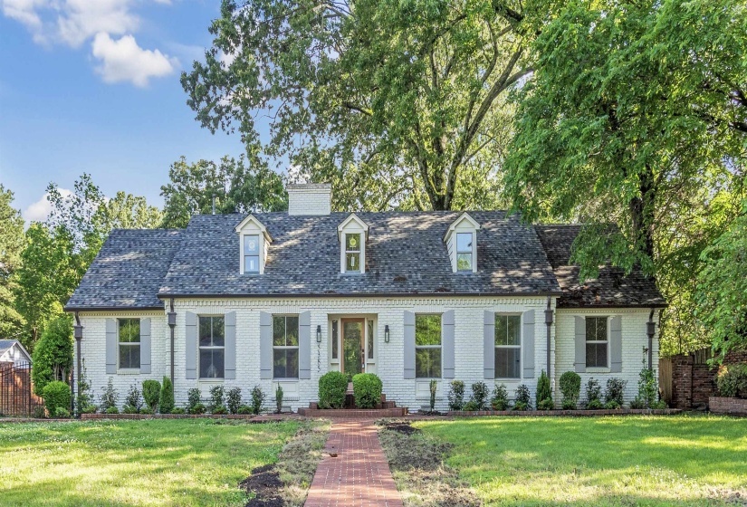 Cape cod-style house featuring brick siding, a chimney, and a front yard