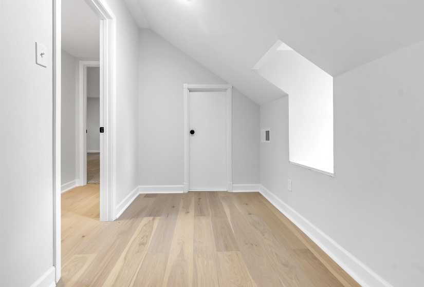 Additional living space with lofted ceiling, light wood-style floors, and baseboards
