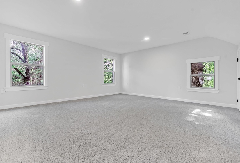Carpeted empty room with baseboards, vaulted ceiling, and recessed lighting