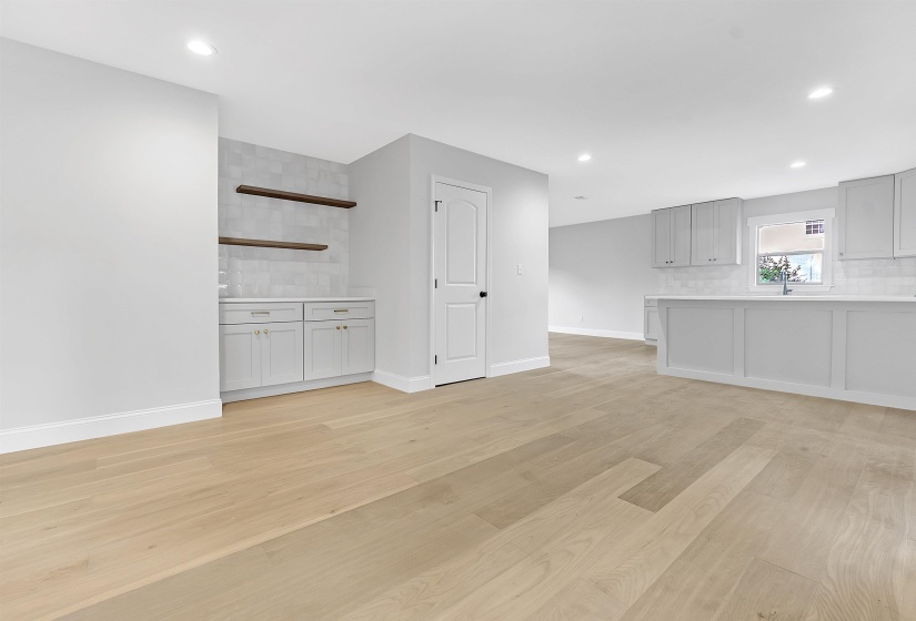 Unfurnished living room with light wood-style flooring, baseboards, recessed lighting, and a sink