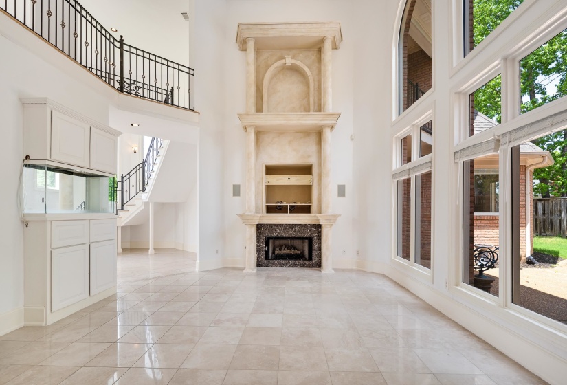 Unfurnished living room with a towering ceiling, baseboards, light marble finish floors, stairway, and a premium fireplace