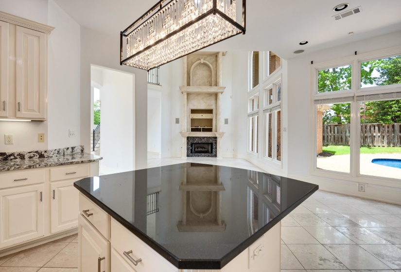 Kitchen featuring a kitchen island, a fireplace, light tile patterned floors, dark stone countertops, and open floor plan