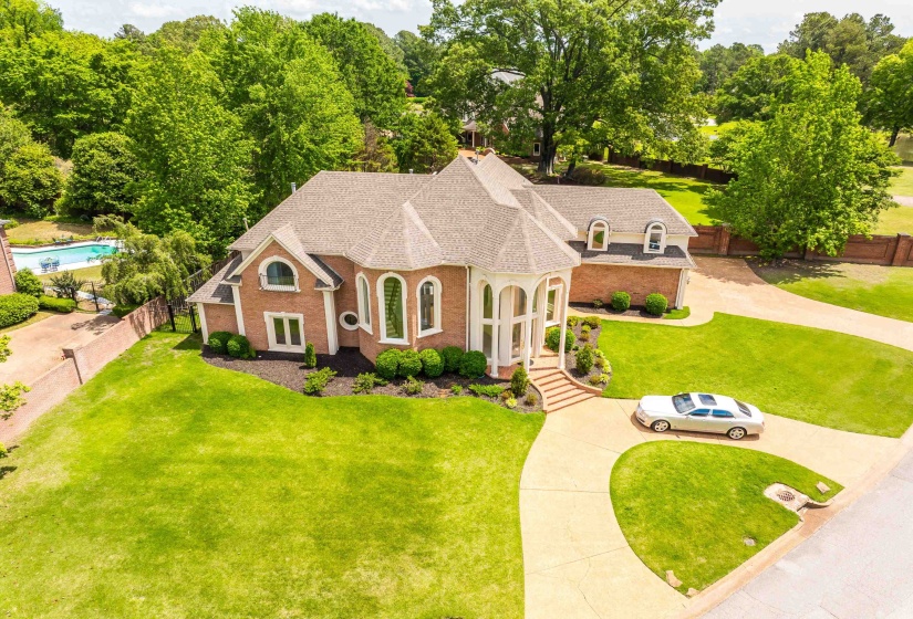 French country style house featuring a shingled roof, brick siding, and concrete driveway