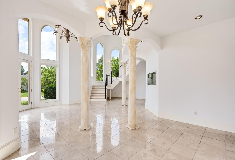 Spare room with a high ceiling, light tile patterned flooring, arched walkways, stairs, and a chandelier