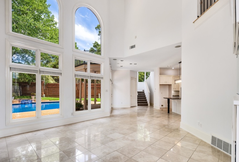 Unfurnished living room with a towering ceiling, stairway, and baseboards