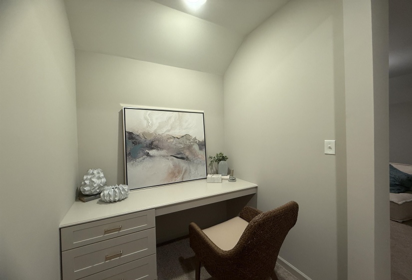 Office space featuring vaulted ceiling, built in study area, and carpet floors