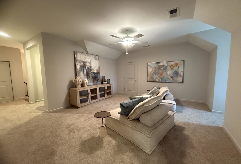 Carpeted living area with vaulted ceiling and a ceiling fan