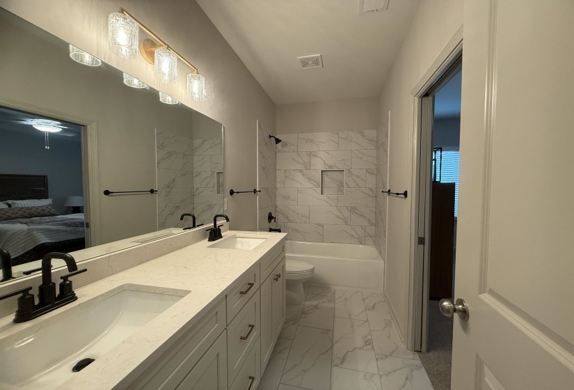 Ensuite bathroom with double vanity,  shower combination, and light marble finish floors