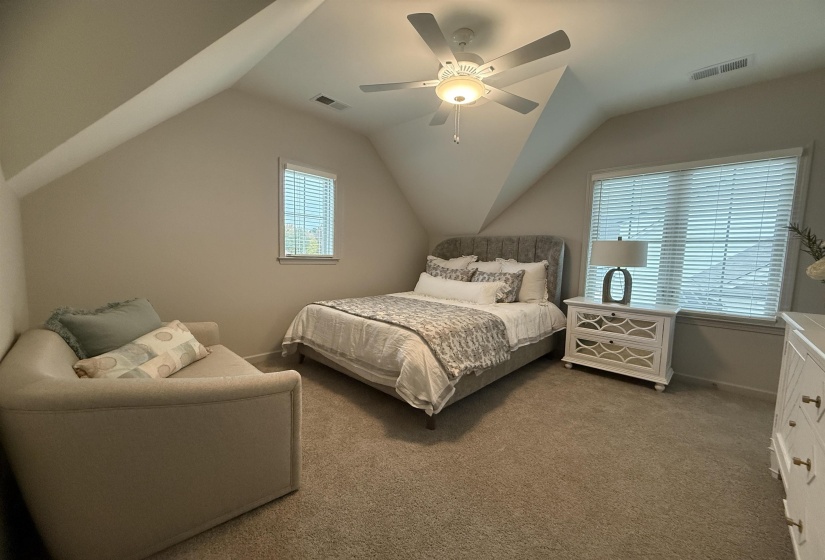 Carpeted bedroom with vaulted ceiling and ceiling fan