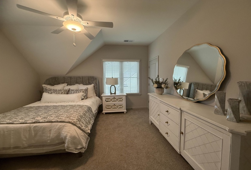 Bedroom with a ceiling fan, vaulted ceiling, and dark colored carpet