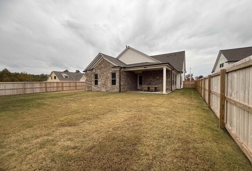 Back of house with a fenced backyard, a patio area, brick siding, and roof with shingles