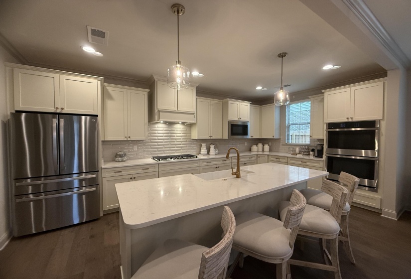 Kitchen with crown molding, stainless steel appliances, tasteful backsplash, dark wood-style floors, and pendant lighting
